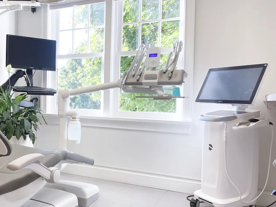 A treatment room with a dental chair, overhead monitor and chairside screen.